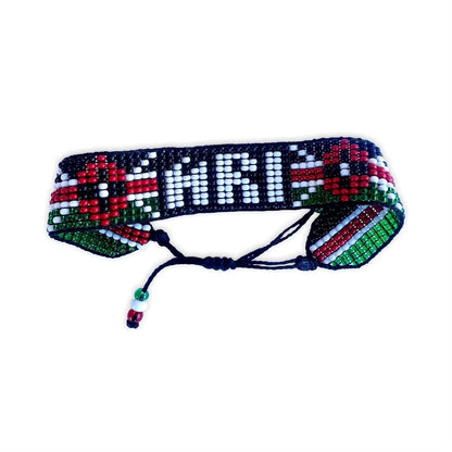 Top view of a colorful hand-beaded bracelet with red, white, green, and black beads, featuring a geometric pattern.