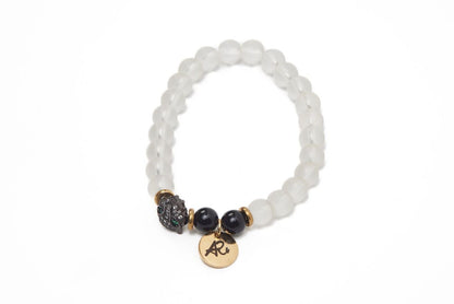 White beaded bracelet with gold accents, black beads, and a gold charm on a white background.